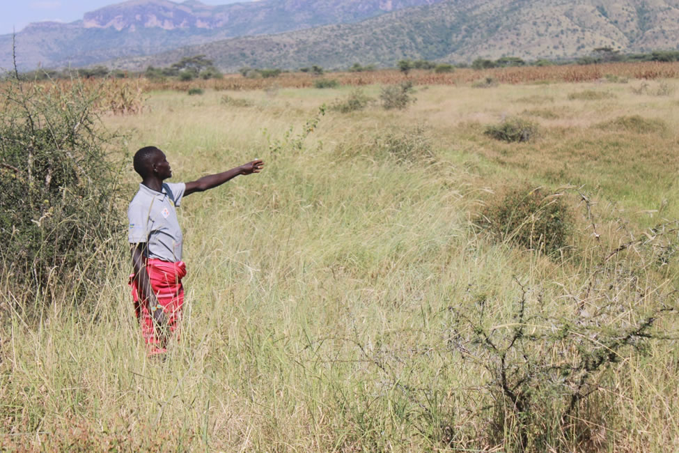 A beneficiary pointing at one of the water ponds which they will desilt